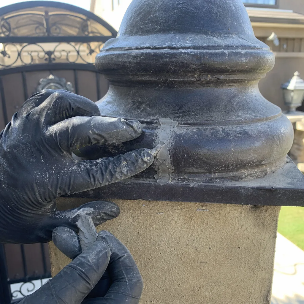Professional applying sealant during a metal gate pillar repair.